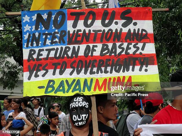 Filipino activist wearing a mask written with messages holds a placard during a rally at Plaza Salamanca to coincide with the Fourth of July...