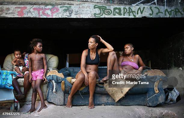 Residents Luiza, Janubie, Leiticia and Lucas sit beneath an overpass near their houses in an impoverished area in the unpacified Complexo da Mare...