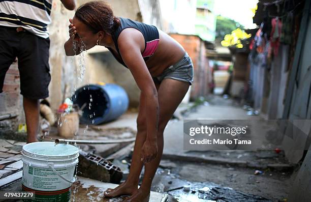 Resident Janubie washes her face with fresh water from an open pipe near her house in an impoverished area in the unpacified Complexo da Mare slum...