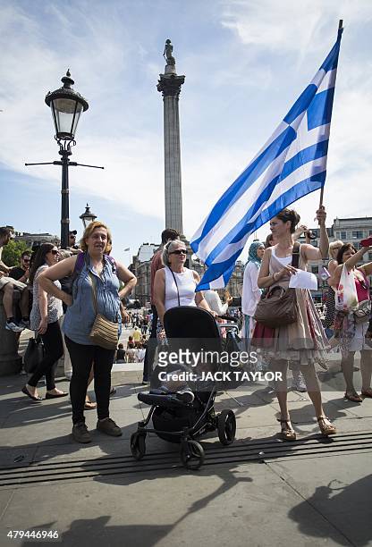 An anti-austerity demonstrator waves the greek flag at a rally in Trafalgar Square in central London on July 4, 2015 in solidarity with those voting...