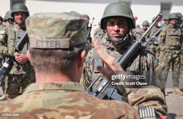 John Etter from Fort Smith, Arkansas with the U.S. Army's 130th Engineer Brigade salutes a graduating Afghan National Army soldier while...