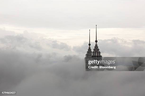The pinnacles of the Petronas Twin Towers protrude through low clouds in Kuala Lumpur, Malaysia, on Tuesday, March 18, 2014. Malaysia, aspiring to...