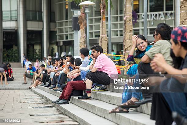 People sit outside the Suria KLCC shopping mall in Kuala Lumpur, Malaysia, on Tuesday, March 18, 2014. Malaysia, aspiring to become a developed...