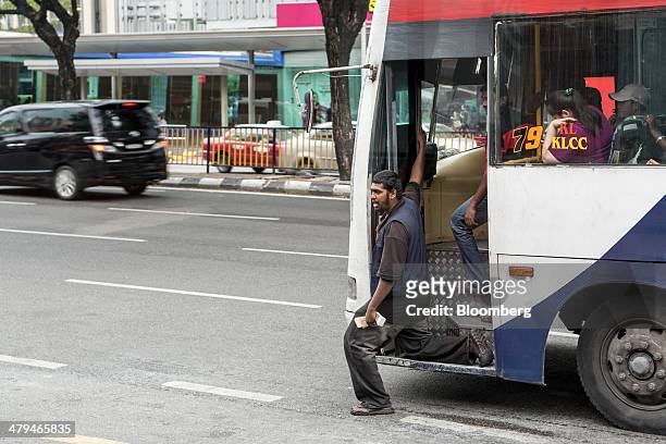 The conductor of a bus operated by Rapid Bus Sdn. Bhd. Calls for passengers in Kuala Lumpur, Malaysia, on Tuesday, March 18, 2014. Malaysia, aspiring...