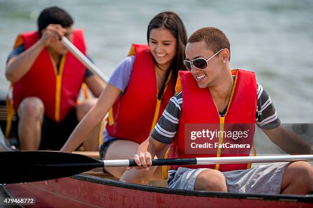 young teenager friends on a canoe trip - teens canoeing stock pictures, royalty-free photos & images