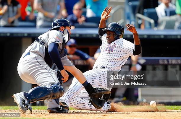Pinch runner Jose Pirela of the New York Yankees slides home to score the game winning run in the ninth inning as Curt Casali of the Tampa Bay Rays...