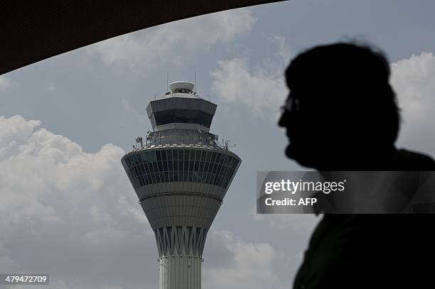 Passenger walks before the Air traffic control tower at Kuala Lumpur International Airport in Sepang, outside Kuala Lumpur on March 19, 2014. The...