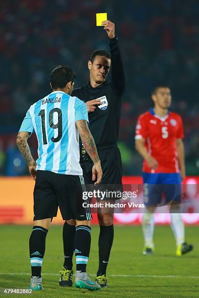 Referee Wilmar Roldan shows a yellow card to Ever Banega of Argentina during the 2015 Copa America Chile Final match between Chile and Argentina at...