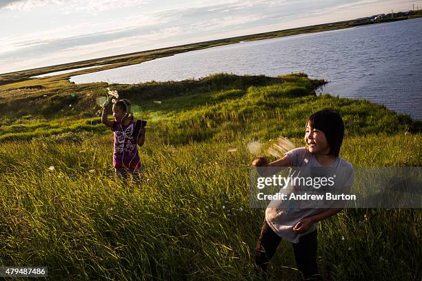 Yupik children play in the grass late in the evening on July 3, 2015 in Newtok, Alaska. Newtok is one of several remote Alaskan villages that is...