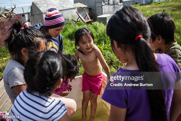 Yupik children play in a container filled with fresh water on July 3, 2015 in Newtok, Alaska. Newtok is one of several remote Alaskan villages that...