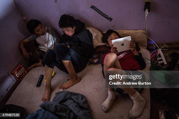 Yupik children play on their tablets in a one room house on July 3, 2015 in Newtok, Alaska. Newtok is one of several remote Alaskan villages that is...