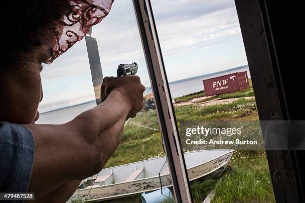 Noah Carl plays with guns while hanging out at his friend's house on July 3, 2015 in Newtok, Alaska. Newtok is one of several remote Alaskan villages...