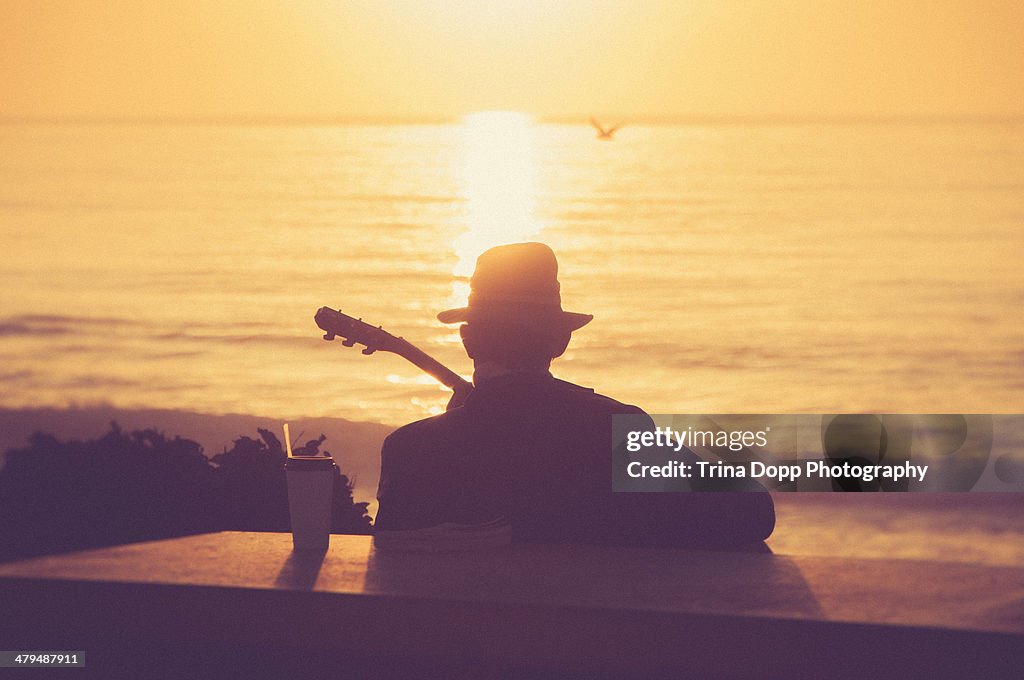 Silhouetted Man Playing Guitar at Sunset