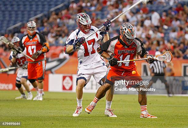 Justin Pennington of the Denver Outlaws and Brodie Merrill of the Boston Cannons compete for the ball during their MLL game at Sports Authority Field...