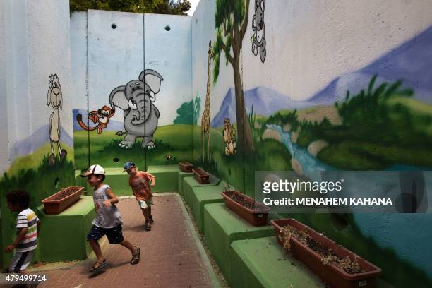 Children play at kindergarten surrounded by decorated concrete blast walls designed to protect from rocket and mortar fire, on June 24 in the...