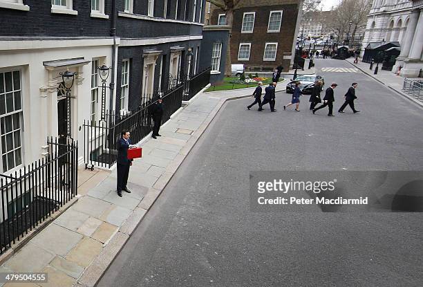 The Chancellor of the Exchequer George Osborne holds the budget box as his Treasury team cross Downing Street on March 19, 2014 in London, England....
