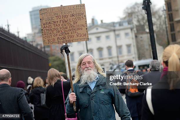 Man holds a placard outside Parliment ahead of the Budget on March 19, 2014 in London, England. Later The Chancellor of the Exchequer George Osborne...