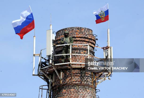 Russian soldier patrols on a chimney with Russian flags at the Ukrainian navy headquarters in the Crimean city of Sevastopol on March 19, 2014....