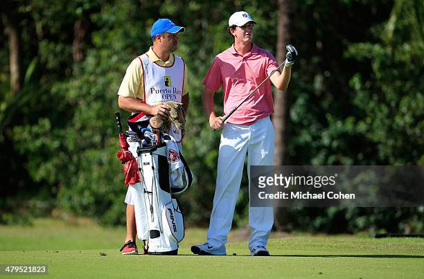 Austen Truslow , an amateur, stands with his caddie Joe Sabatino and prepares to hit a shot during the first round of the Puerto Rico Open presented...