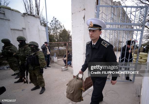 Ukrainian officer leaves as Russian soldiers stand guard after they took control of the Ukrainian navy south headquarters base in Novoozerne on March...