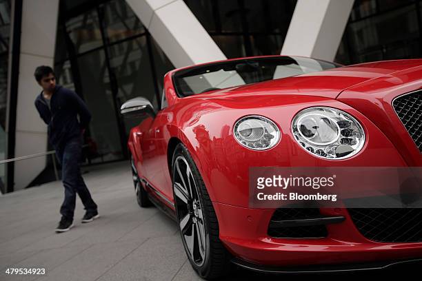 Pedestrian looks at a Bentley Continental GT convertible automobile, produced by Bentley Motors Ltd., following a news conference to announce the...