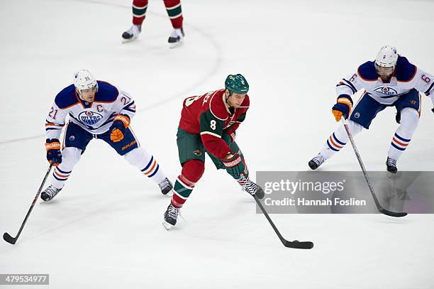 Cody McCormick of the Minnesota Wild controls the puck against Andrew Ference and Jesse Joensuu of the Edmonton Oilers during the game on March 11,...