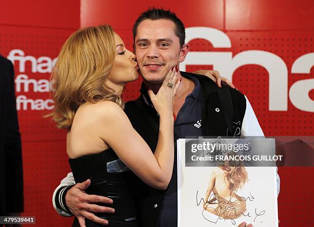 Australian singer Kylie Minogue kisses a fan during a dedication session on March 19, 2014 in Paris. AFP PHOTO / FRANCOIS GUILLOT