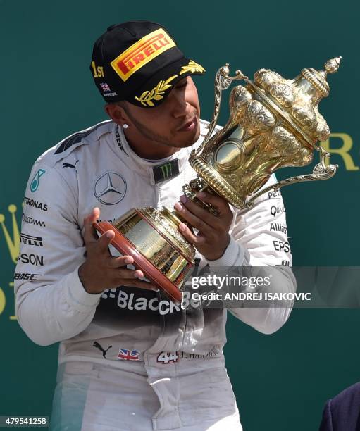 Mercedes AMG Petronas F1 Team's British driver Lewis Hamilton kisses the trophy on the podium after winning the British Formula One Grand Prix at the...