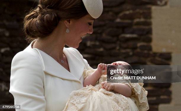 Britain's Catherine, Duchess of Cambridge, carries her daughter, Princess Charlotte of Cambridge after taking her out of a pram as they arrive for...