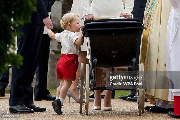 Catherine, Duchess of Cambridge and Prince William, Duke of Cambridge stand as Prince George of Cambridge looks into Princess Charlotte of...