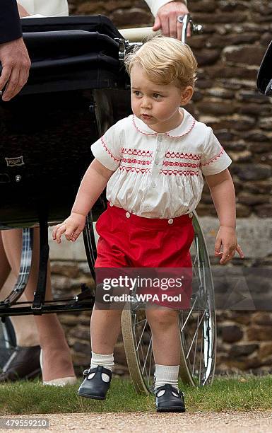 Prince George of Cambridge stands near Princess Charlotte of Cambridge's pram at the Church of St Mary Magdalene on the Sandringham Estate after the...