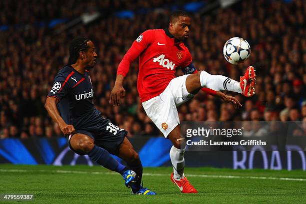 Patrice Evra of Manchester United competes with Leandro Salino of Olympiacos during the UEFA Champions League Round of 16 second round match between...
