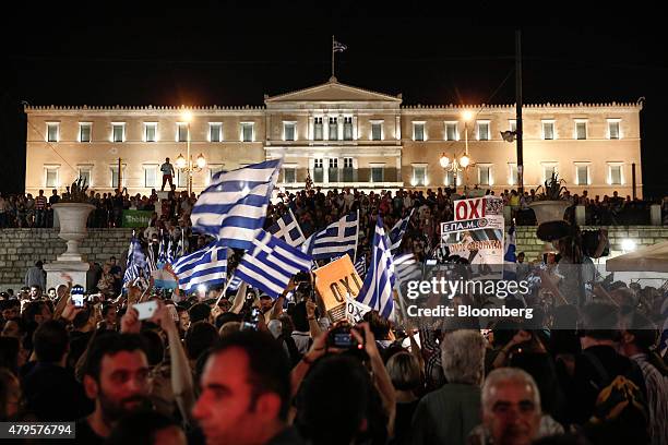 Supporters of the 'No" vote wave Greek national flags outside the parliament after early results show the "OXI" or "No" vote ahead in the Greek...