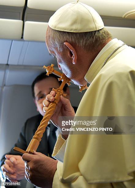 Pope Francis kisses a cross received as a gift from Bolivian journalist Cecilia Dorado Nava, as he welcomes the journalists on board the flight to...