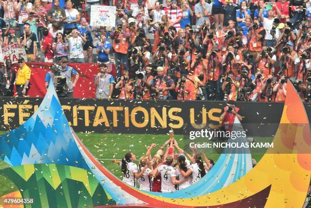 The USA team celebrates with the World Cup trophy on the podium after defeating Japan in the 2015 FIFA Women's World Cup final at BC Place Stadium in...