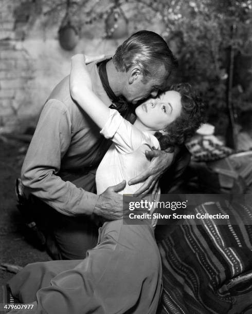 American actor Gary Cooper embracing Susan Hayward in a promotional portrait for 'Garden Of Evil', directed by Henry Hathaway, 1954.