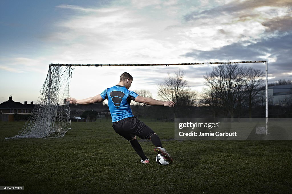 Mixed race male taking a penalty kick