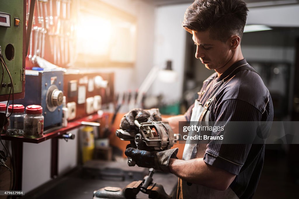 Manual worker repairing electric motor in a workshop.