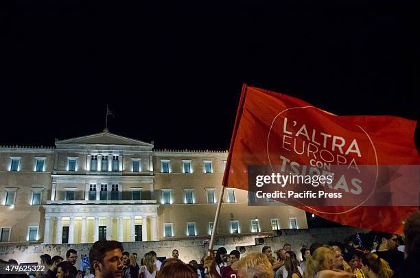 Demonstrator holds a flag with the phrase 'L' Altra Europa Con Tsipras' . Greek people celebrate after hearing that the majority of the voters voted...