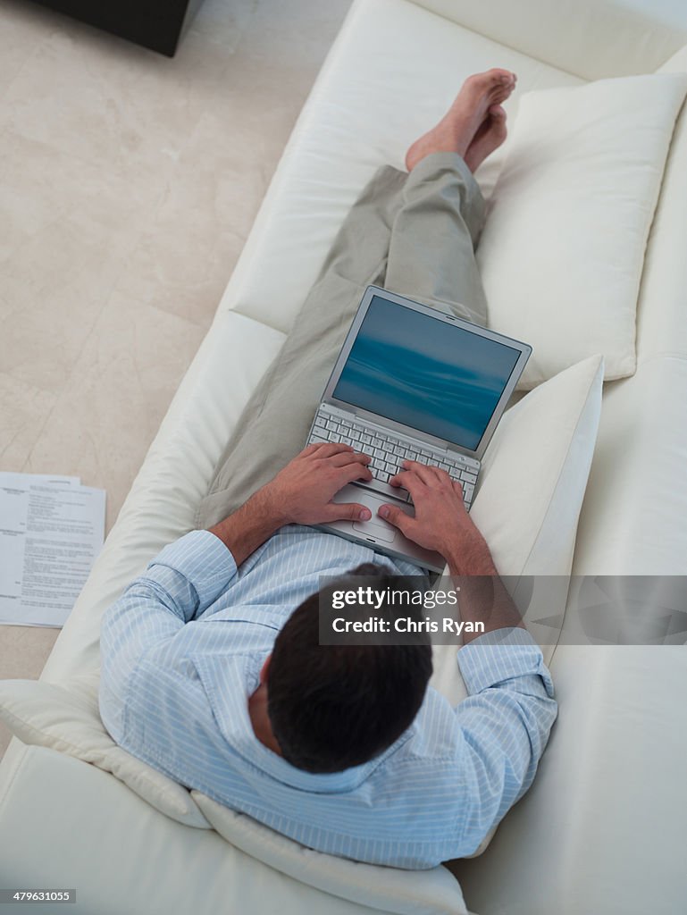 Man working on his laptop while relaxing at home