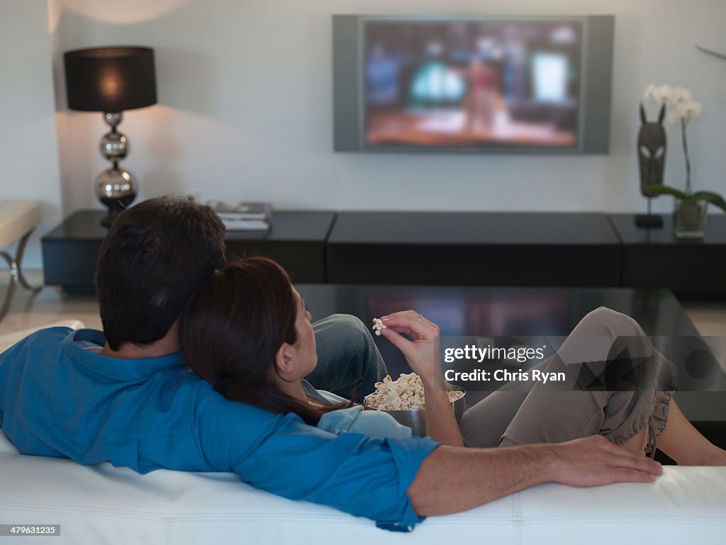 Couple watching television together and eating popcorn