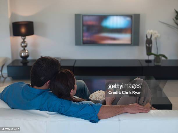 couple watching television together and eating popcorn - big screen television stock pictures, royalty-free photos & images