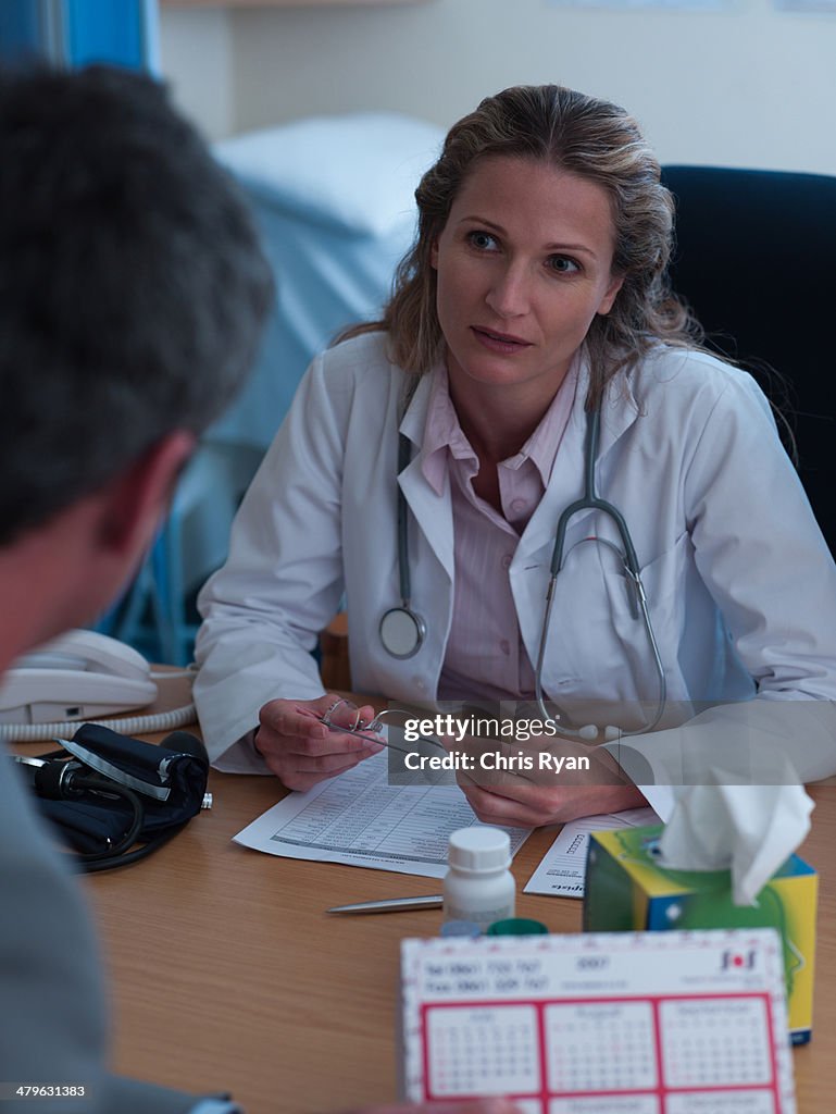 Médica na Mesa a falar para homem