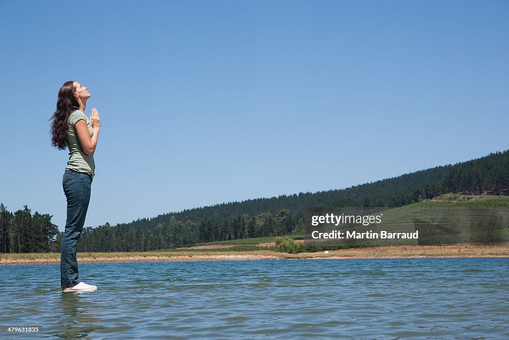 Profile of woman standing on water praying