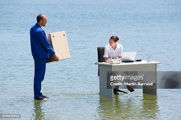 man delivering cardboard box to woman at desk on water - business flood stock pictures, royalty-free photos & images