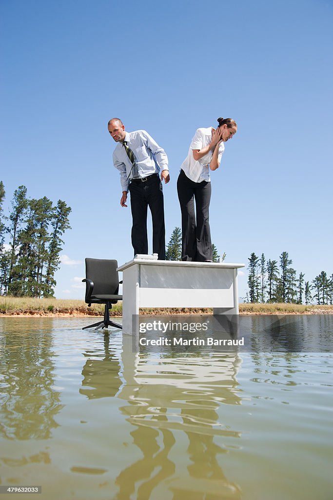 Businesswoman and man standing on desk on water