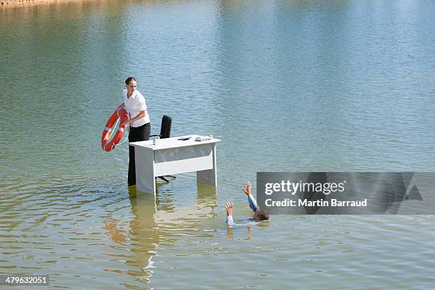 geschäftsfrau sitzen am schreibtisch im wasser mit schwimmwesten - befreiung stock-fotos und bilder