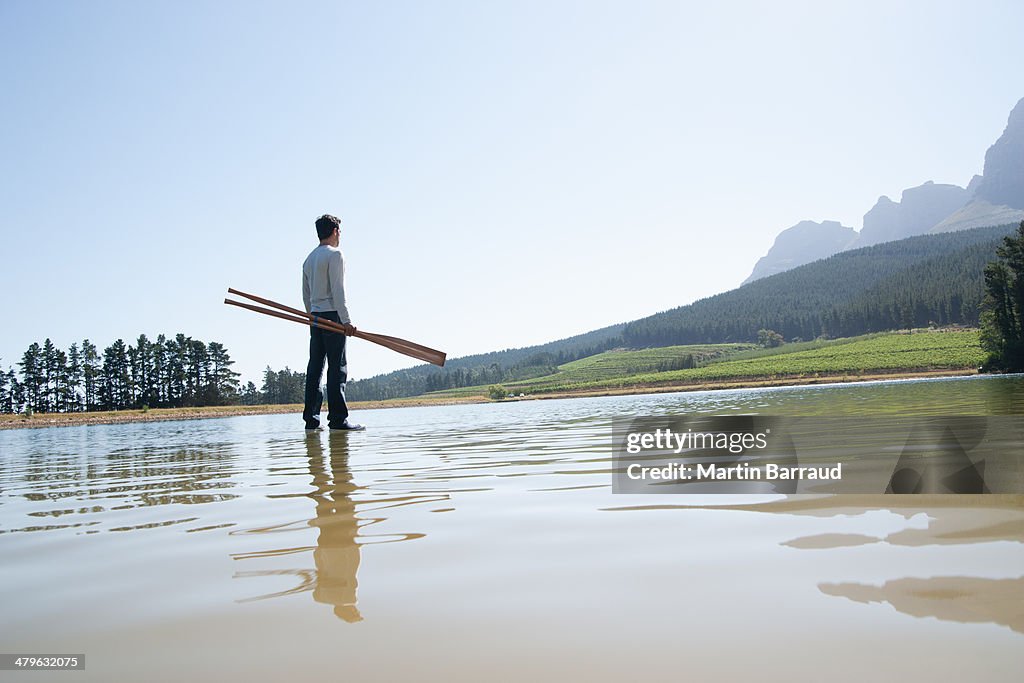 Man standing on water with oars