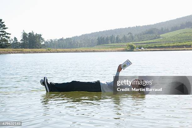 man lying down on water reading book - illusie stockfoto's en -beelden