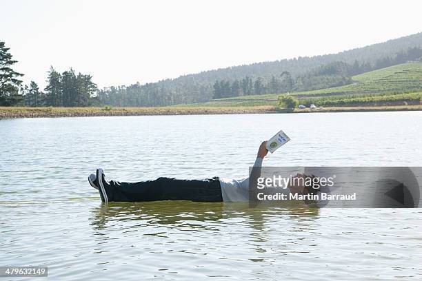 man lying down on water reading book - mystery book stock pictures, royalty-free photos & images